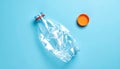 Crushed Clear Plastic Water Bottle with Orange Cap Separated on Blue Background empty Royalty Free Stock Photo