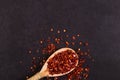 Crushed dried chili peppers in a wooden spoon scattered on a black background. Concept, copy space