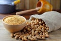 Crushed and ground peanuts in ceramic bowl forming flour on rustic wooden table