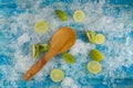 Crushed ice cubes and lemon, kiwi, wooden spoon on vintage blue