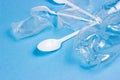 Crushed plastic spoons, forks, bottles and cups as a disposable waste on bright blue background. Environmental pollution Royalty Free Stock Photo