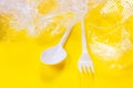 Crushed plastic spoons, forks, bottles and cups as a disposable waste on bright yellow background. Environmental pollution Royalty Free Stock Photo