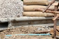 Crushed rock for construction and row of raw cement bag stack in construction site.