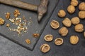 Crushed walnuts and a rusty old hammer on a stone board. Nut shell and whole nuts on the table Royalty Free Stock Photo