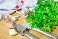 Crushing garlic to add to the dish. Whole and chopped garlic on a cutting Board made from natural oak. Fresh parsley. Royalty Free Stock Photo