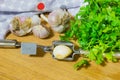 Crushing garlic to add to the dish. Whole and chopped garlic on a cutting Board made from natural oak. Fresh parsley. Royalty Free Stock Photo