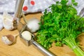 Crushing garlic to add to the dish. Whole and chopped garlic on a cutting Board made from natural oak. Fresh parsley. Royalty Free Stock Photo