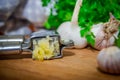 Crushing garlic to add to the dish. Whole and chopped garlic on a cutting Board made from natural oak. Fresh parsley. Royalty Free Stock Photo