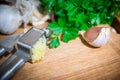 Crushing garlic to add to the dish. Whole and chopped garlic on a cutting Board made from natural oak. Fresh parsley. Royalty Free Stock Photo