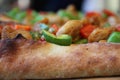 Crust of a slice of Italian Neapolitan pizza topped with tomatoes and green and red peppers Royalty Free Stock Photo