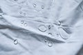 Crustal water droplets shining in the light on white fabric drapery with folds Royalty Free Stock Photo