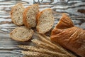 Crusty sliced bread wheat ears on wooden surface Royalty Free Stock Photo