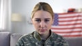 Crying american female soldier looking at camera against US national flag, PTSD Royalty Free Stock Photo