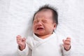 Crying and angry Newborn baby boy lying on white bed at home.Infant baby screaming very hungry or stomach pain. sick asian baby Royalty Free Stock Photo