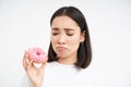 Crying asian woman showing tasty douhnuts and sobbing, being on healthy diet, cant eat junk food, white background Royalty Free Stock Photo