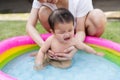 Crying baby carried by mother enjoying in Inflatable pool Royalty Free Stock Photo