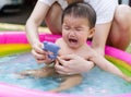 Crying baby carried by mother enjoying in Inflatable pool Royalty Free Stock Photo