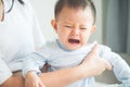 Crying baby in his mother`s hand in bedroom / Royalty Free Stock Photo