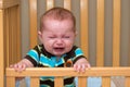 Crying baby standing in his crib