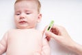 Crying baby with a thermometer. Mom measures the temperature of the baby Close up