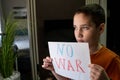 Crying boy asks to stop the war. The child holds a poster