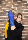 Crying boy and a young woman with yellow-blue painted hands embrace