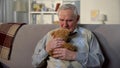 Crying elderly man hugging teddy bear, missing grandchildren, family support Royalty Free Stock Photo