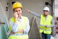 Crying female builder at construction site with displeased foreman