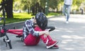 Crying girl in helmet sitting on the park road