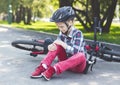 Crying girl is sitting next to her bike