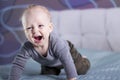 Crying happy baby boy on the bed. Laughing toddler kid looking at camera. Crawling infant in his room Royalty Free Stock Photo
