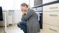 Crying young housewife sitting on floor at kitchen Royalty Free Stock Photo