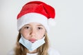 Crying kid with red santa claus hat and mask isolated on white background. Sad child face with surgical mask. Christmas covid 19 Royalty Free Stock Photo