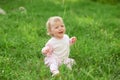 Crying little girl sitting on green grass, looking for mom. Royalty Free Stock Photo