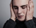 Unhappy crying man with dropping tears on the face with headache holding the head. Closeup studio portrait on grey background. Royalty Free Stock Photo