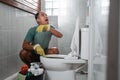 crying man wearing gloves when brushing dirty toilet