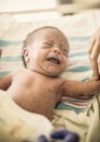 Crying Newborn infant baby boy in a hospital bed