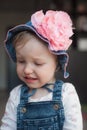 Crying offended baby girl in summer hat. Panama with a big pink flower