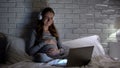 Crying pregnant woman watching movie at night, feeling lonely and depressed