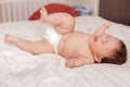 Crying screaming Asian mixed race baby girl four months old lying on bed in bedroom on her back