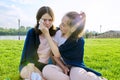 Crying teenager girl and comforting girlfriend, teenagers sitting on the grass in park