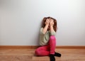 Crying unhappy kid girl sitting on the floor with closed face