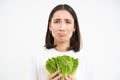 Crying woman holding vegetable, sitting on diet and eating cabbage instead of junk food, white background Royalty Free Stock Photo