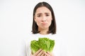 Crying woman holding vegetable, sitting on diet and eating cabbage instead of junk food, white background Royalty Free Stock Photo