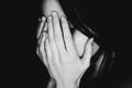Crying young girl covers her face with hands black white