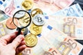 Crypto currency Bitcoin trough magnifying glass on real traditional euros background. investment, business,