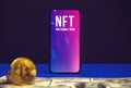 Cryptoart and cryptographic, NFT token logo on the screen of modern mobile phone, office table with dollar and crypto