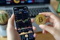 Cryptocurrency concept Hand holding Bitcoin, smartphone displays stock chart