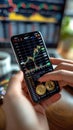 Cryptocurrency concept Hand holding Bitcoin, smartphone displays stock chart