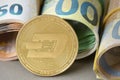 Cryptocurrency Dash golden coin on the background of rolled euro bills. Royalty Free Stock Photo